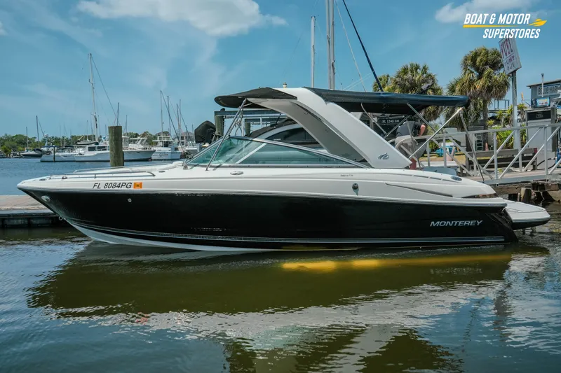 Slide: The Image of 2012 Monterey 264FS boat docked at marina, featuring sleek black and white design. - 7