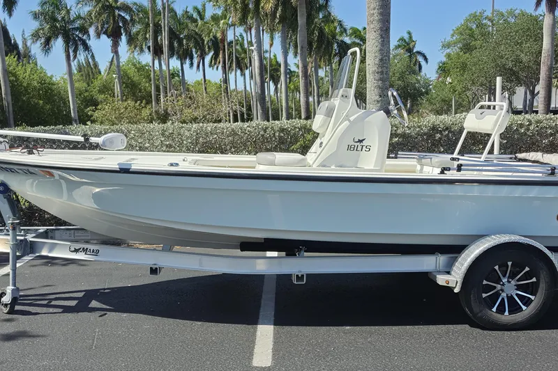 The Image of 2023 Mako 18 LTS boat on trailer, parked outdoors with palm trees in background. - 0