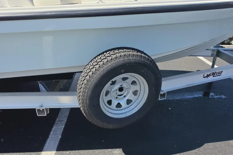 Slide: The Image of 2023 Mako 18 LTS boat trailer with tire, parked on asphalt. - 18