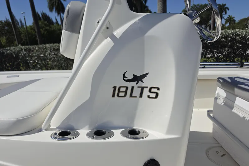 Slide: The Image of 2023 Mako 18 LTS boat console with logo and cup holders, outdoors. - 2