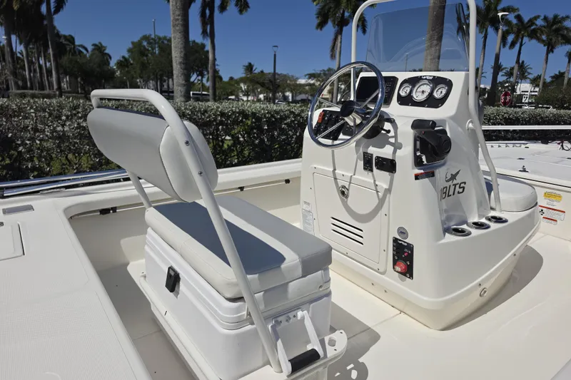 Slide: The Image of 2023 Mako 18 LTS boat interior with steering console and seating, surrounded by palm trees. - 5
