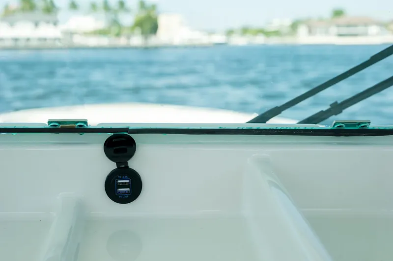 Slide: The Image of 2026 Sailfish 312 CC boat dashboard with USB ports, overlooking serene water and distant shoreline. - 16