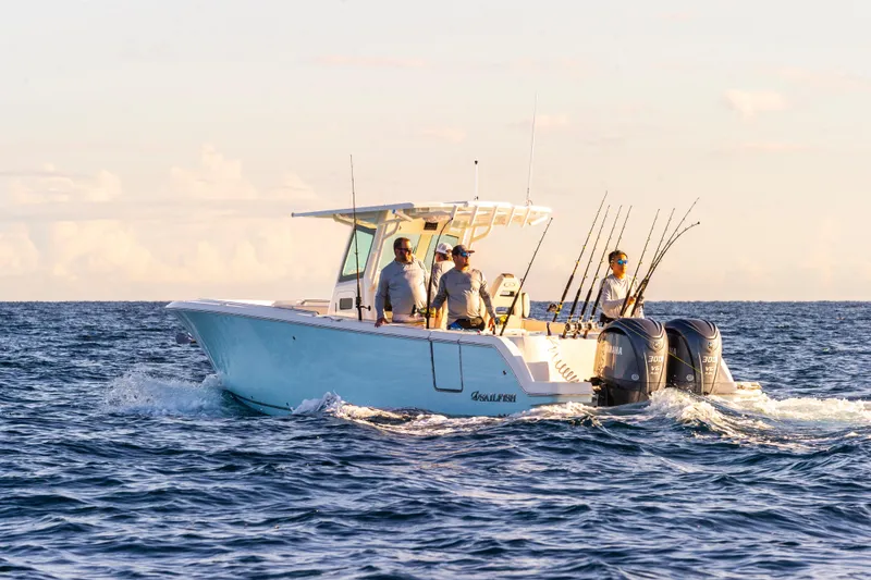 Slide: The Image of 2026 Sailfish 312 CC boat with anglers, cruising on open water at sunset. - 3
