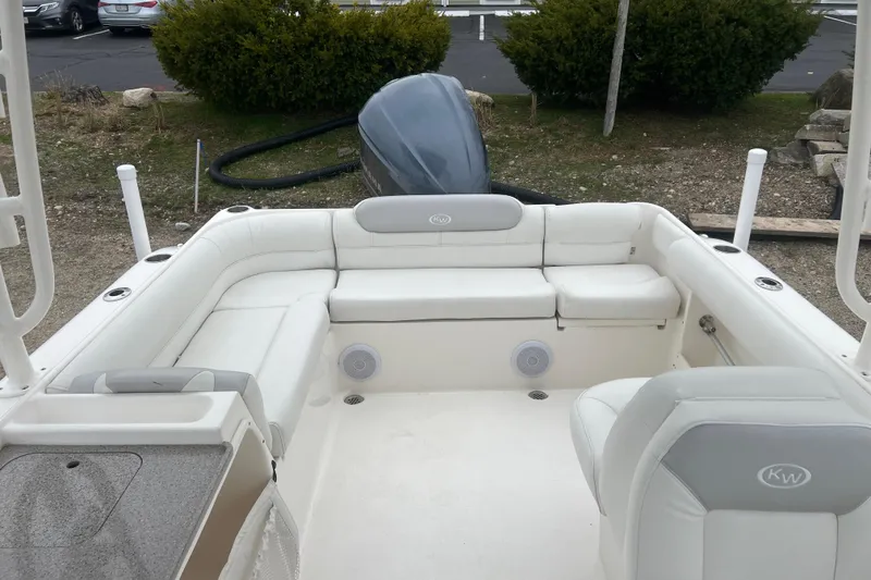 Slide: The Image of 2022 Key West 239 DFS boat interior with white seating and motor, parked outdoors. - 9