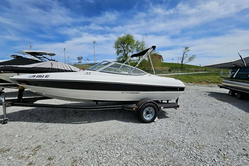 The Image of 2015 Stingray 180 RX boat on trailer, parked outdoors under a clear blue sky. - 0