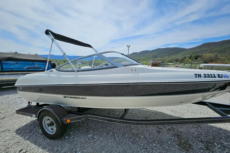 Slide: The Image of 2015 Stingray 180 RX boat on trailer, parked outdoors with scenic mountain backdrop. - 2