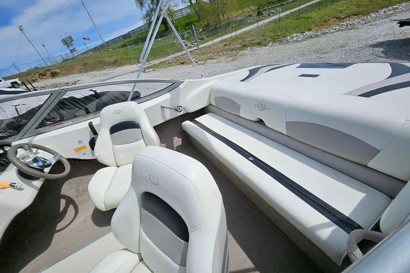 Slide: The Image of 2015 Stingray 180 RX boat interior with white seating and steering wheel, parked outdoors. - 6
