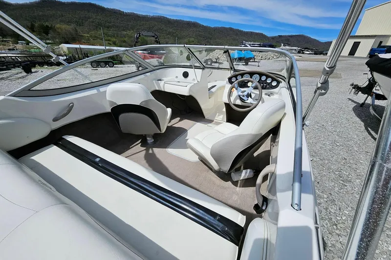 Slide: The Image of 2015 Stingray 180 RX boat interior with steering wheel and seating, parked outdoors. - 7