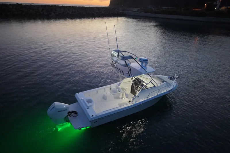 Slide: The Image of 1985 Chris-Craft 21 Scorpion Cuddy boat illuminated on calm water at sunset. - 10