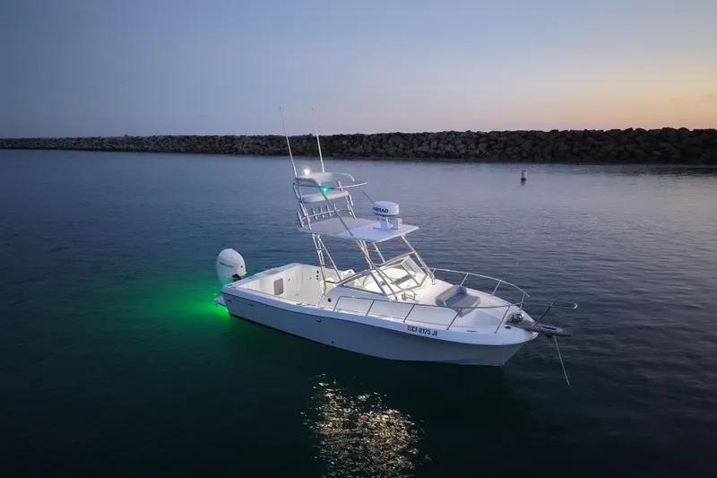 Slide: The Image of 1985 Chris-Craft 21 Scorpion Cuddy boat illuminated on calm water at dusk. - 11