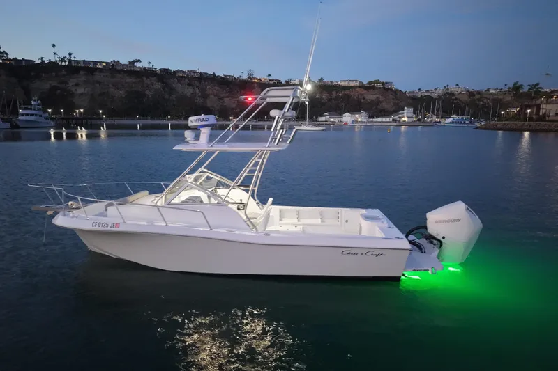 Slide: The Image of 1985 Chris-Craft 21 Scorpion Cuddy boat with green underwater lights in a marina at dusk. - 14