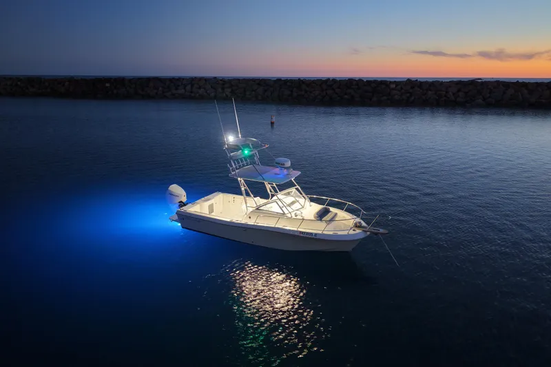 Slide: The Image of 1985 Chris-Craft 21 Scorpion Cuddy boat illuminated on calm water at sunset. - 17