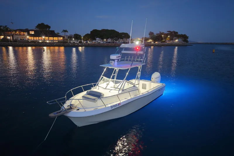 Slide: The Image of 1985 Chris-Craft 21 Scorpion Cuddy boat illuminated on calm water at dusk. - 19
