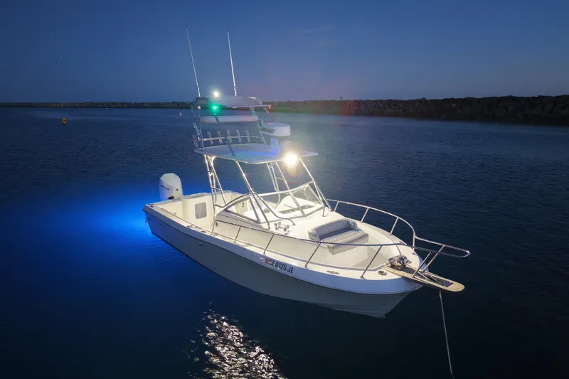 Slide: The Image of 1985 Chris-Craft 21 Scorpion Cuddy boat illuminated on calm water at dusk. - 20