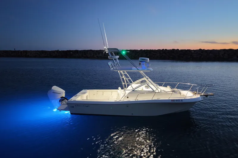 Slide: The Image of 1985 Chris-Craft 21 Scorpion Cuddy boat illuminated on calm water at dusk. - 21