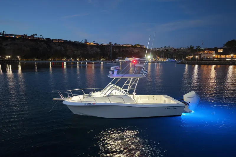Slide: The Image of 1985 Chris-Craft 21 Scorpion Cuddy boat illuminated on calm water at dusk. - 22