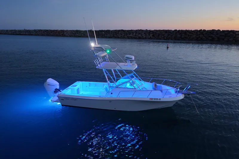 Slide: The Image of 1985 Chris-Craft 21 Scorpion Cuddy boat illuminated on calm water at dusk. - 27