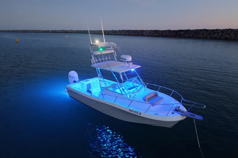 Slide: The Image of 1985 Chris-Craft 21 Scorpion Cuddy boat illuminated with blue lights on calm water. - 28