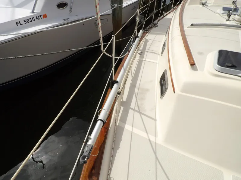 Slide: The Image of 1990 Island Packet 32 sailboat deck with wooden handrails and rigging, docked beside another boat. - 30