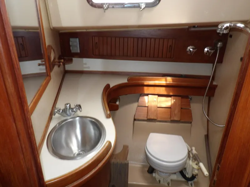 Slide: The Image of 1990 Island Packet 32 yacht bathroom with sink, toilet, and wooden cabinetry. - 19