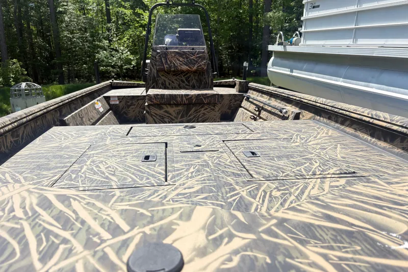 Slide: The Image of 2022 Lowe Roughneck 1860CC boat with camouflage design, docked outdoors. - 4