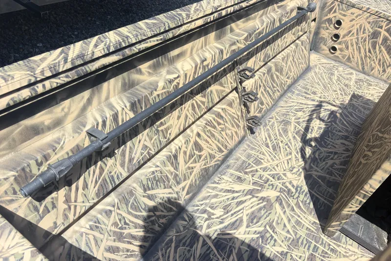 Slide: The Image of 2022 Lowe Roughneck 1860CC boat interior with camouflage design and rod holders. - 8