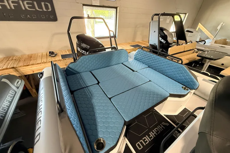Slide: The Image of 2026 Highfield ADV7 boat with blue cushioned seating and Suzuki outboard motor in showroom. - 25