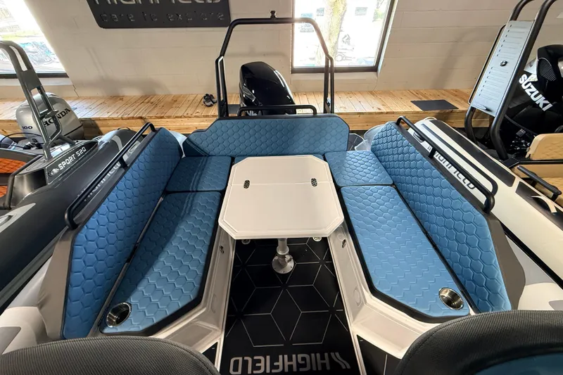 Slide: The Image of 2026 Highfield ADV7 boat interior with blue hexagonal-patterned seating and central table. - 7
