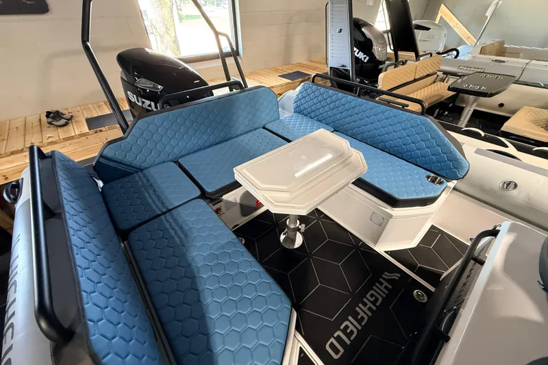 Slide: The Image of 2026 Highfield ADV7 boat interior with blue hexagonal-patterned seating and a central table. - 8