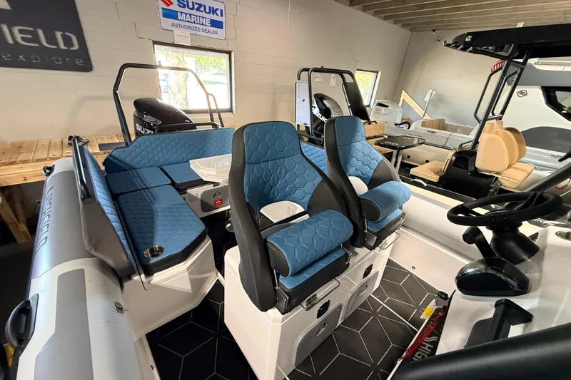 Slide: The Image of 2026 Highfield ADV7 boat interior with blue seating and Suzuki engine in showroom. - 9