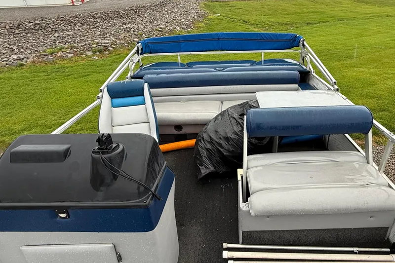 Slide: The Image of 1989 Godfrey Aqua Patio 2424 pontoon boat with blue and white seating, parked on grass. - 6