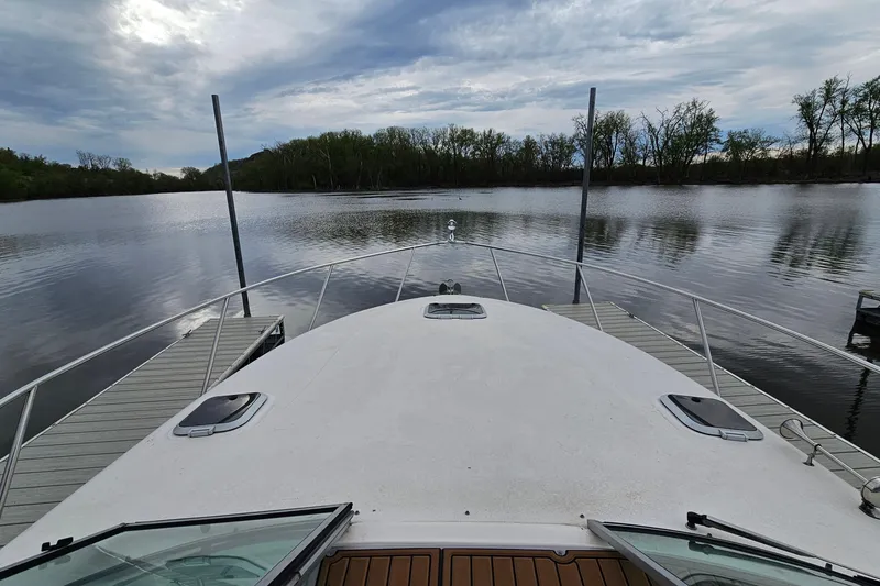 Slide: The Image of 2004 Rinker Fiesta Vee 312 docked on a calm lake under a cloudy sky. - 16