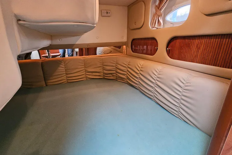 Slide: The Image of Interior cabin of 2004 Rinker Fiesta Vee 312 boat with cushioned seating and porthole window. - 25