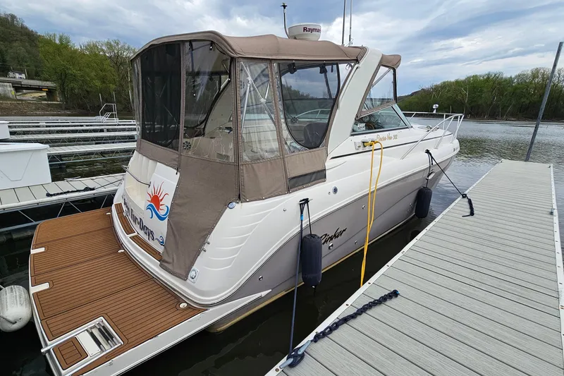 Slide: The Image of 2004 Rinker Fiesta Vee 312 boat docked, featuring a covered cabin and wooden deck. - 3