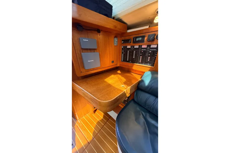 Slide: The Image of Navigation station of 2002 Hunter 386 sailboat with control panels and seating. - 15