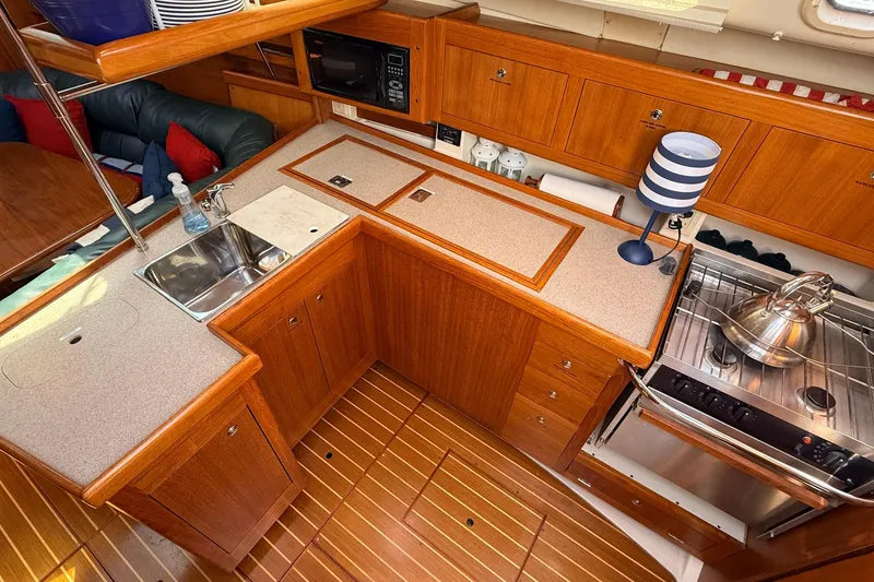 Slide: The Image of Wooden galley kitchen in 2002 Hunter 386 sailboat with stove, sink, and storage cabinets. - 19
