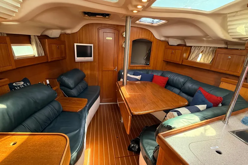 Slide: The Image of Luxurious 2002 Hunter 386 yacht interior with plush seating, wooden finishes, and a mounted TV. - 2