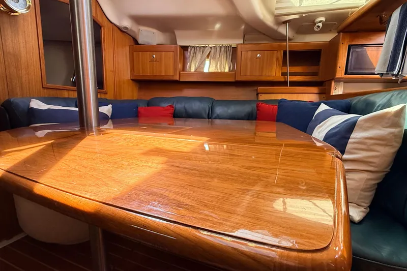 Slide: The Image of Cozy interior of a 2002 Hunter 386 sailboat with polished wood table and cushioned seating. - 4