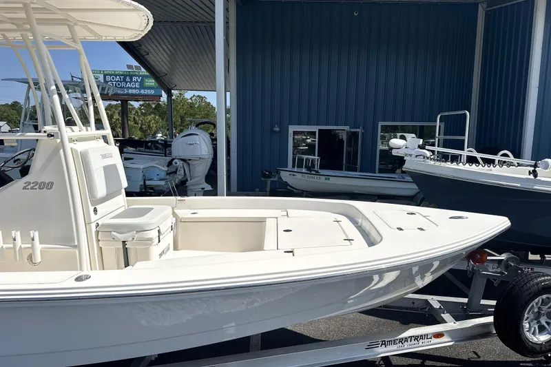 Slide: The Image of 2023 Pathfinder 2200 TRS boat on trailer at dealership, blue building background. - 18