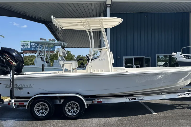 Slide: The Image of 2023 Pathfinder 2200 TRS boat on trailer, parked under a metal canopy. - 2