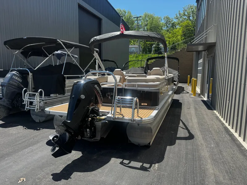 Slide: The Image of 2017 Tahoe LTZ2685 pontoon boat with outboard motor, parked beside a building. - 13