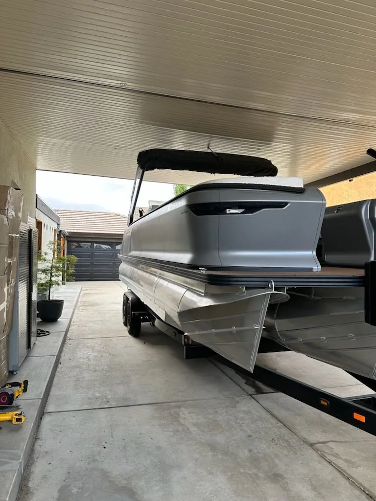 Slide: The Image of 2024 Manitou Switchback pontoon boat on trailer under carport. - 4