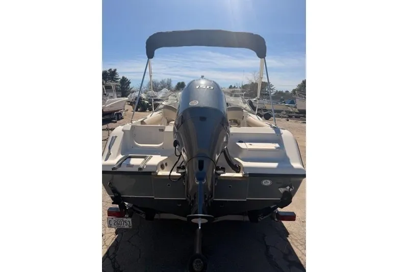 Slide: The Image of 2021 Key West 203 DFS boat with outboard motor and canopy, parked outdoors. - 2