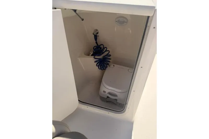Slide: The Image of 2021 Key West 203 DFS boat interior with portable toilet and coiled hose. - 9