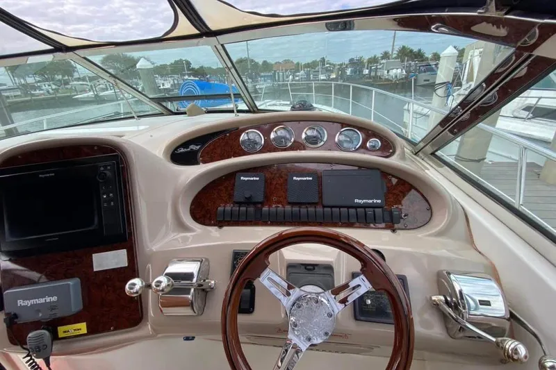 Slide: The Image of 2004 Sea Ray 380 Sundancer helm with Raymarine navigation equipment and wood-accented dashboard. - 5