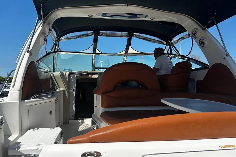 Slide: The Image of 2004 Sea Ray 380 Sundancer interior with seating and helm, featuring a person onboard. - 6