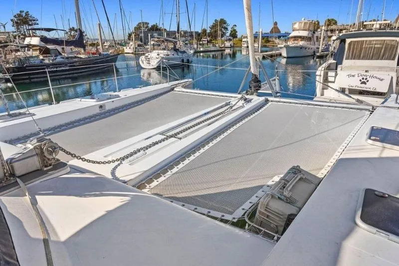 Slide: The Image of 2002 Outremer 55 Light catamaran docked in a marina, showcasing its spacious deck and netting. - 11