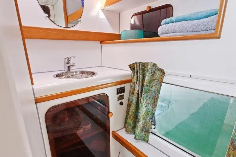 Slide: The Image of Compact bathroom in 2002 Outremer 55 Light yacht with sink, mirror, and storage shelves. - 29
