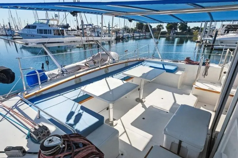 Slide: The Image of Spacious deck of 2002 Outremer 55 Light catamaran, featuring seating and tables, docked at marina. - 4