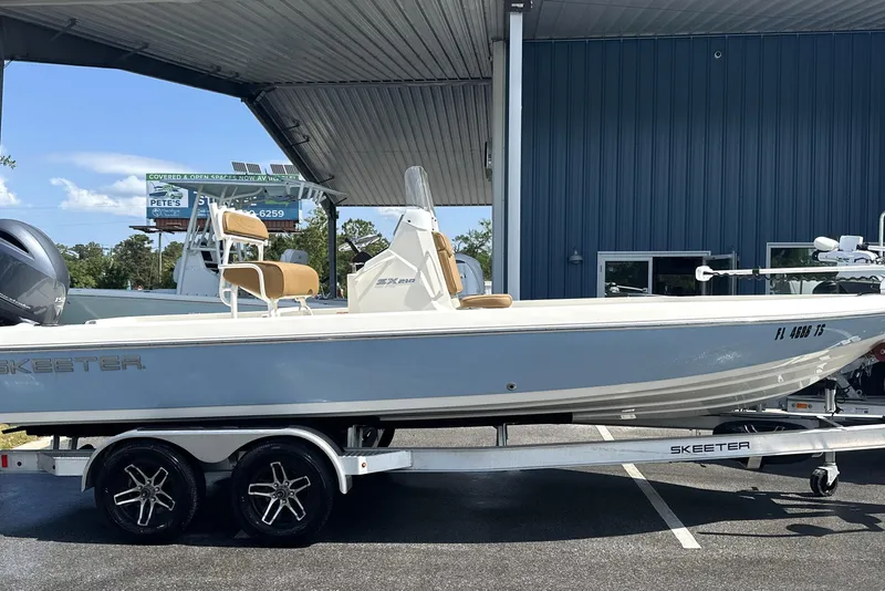 The Image of 2023 Skeeter SX210 boat on trailer, parked outdoors under a metal canopy. - 0